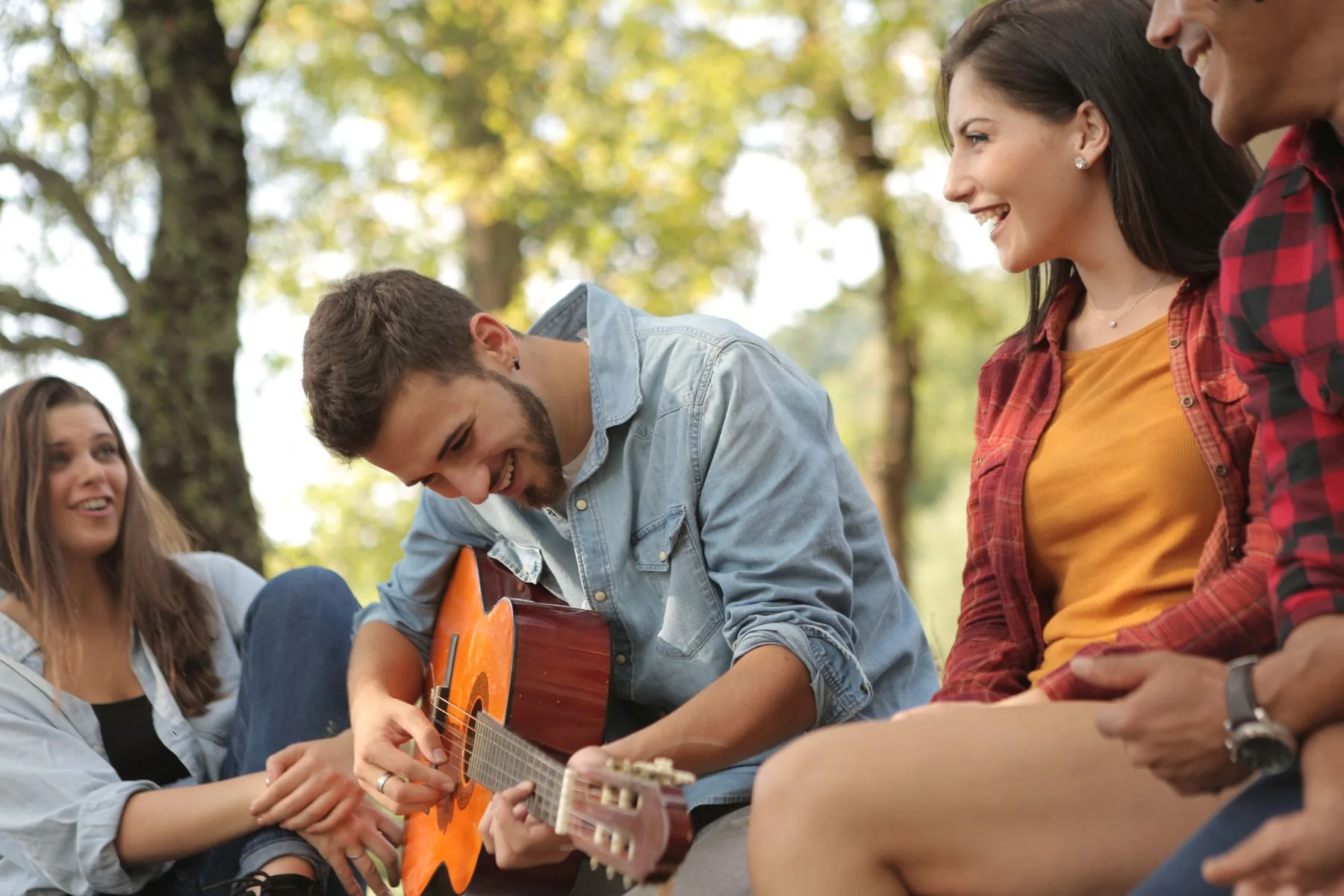 Mladí priatelia sa smejú pri hraní na gitare